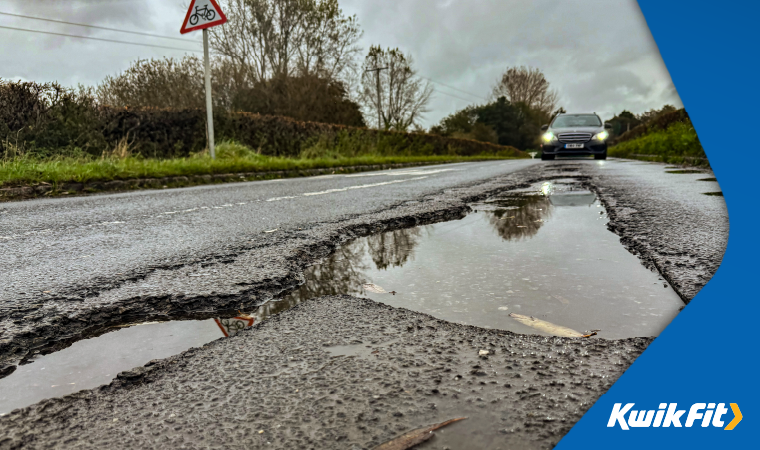 Several very large potholes in the road filled with water