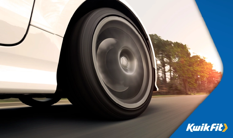 A closeup of a white car's tyres, moving fast.